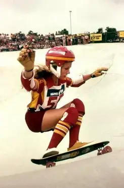 Ellen O'Neal en tenue de compétition en plein saut sur son skate