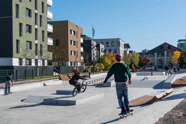 Vue sur le skatepark avec ses modules de glisse et des pratiquants en skate et BMX